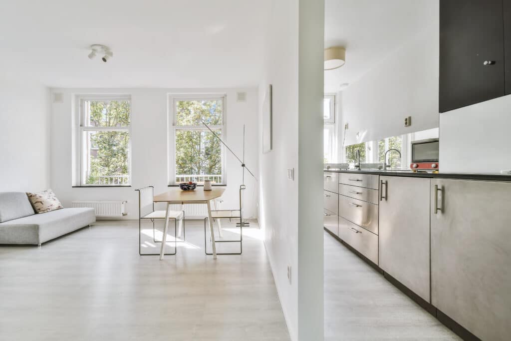 Design intérieur moderne : salon, salle à manger, cuisine ouverte Intérieur moderne lumineux avec salon, salle à manger bois clair et cuisine design gris métal. Fenêtres sur arbres verts.